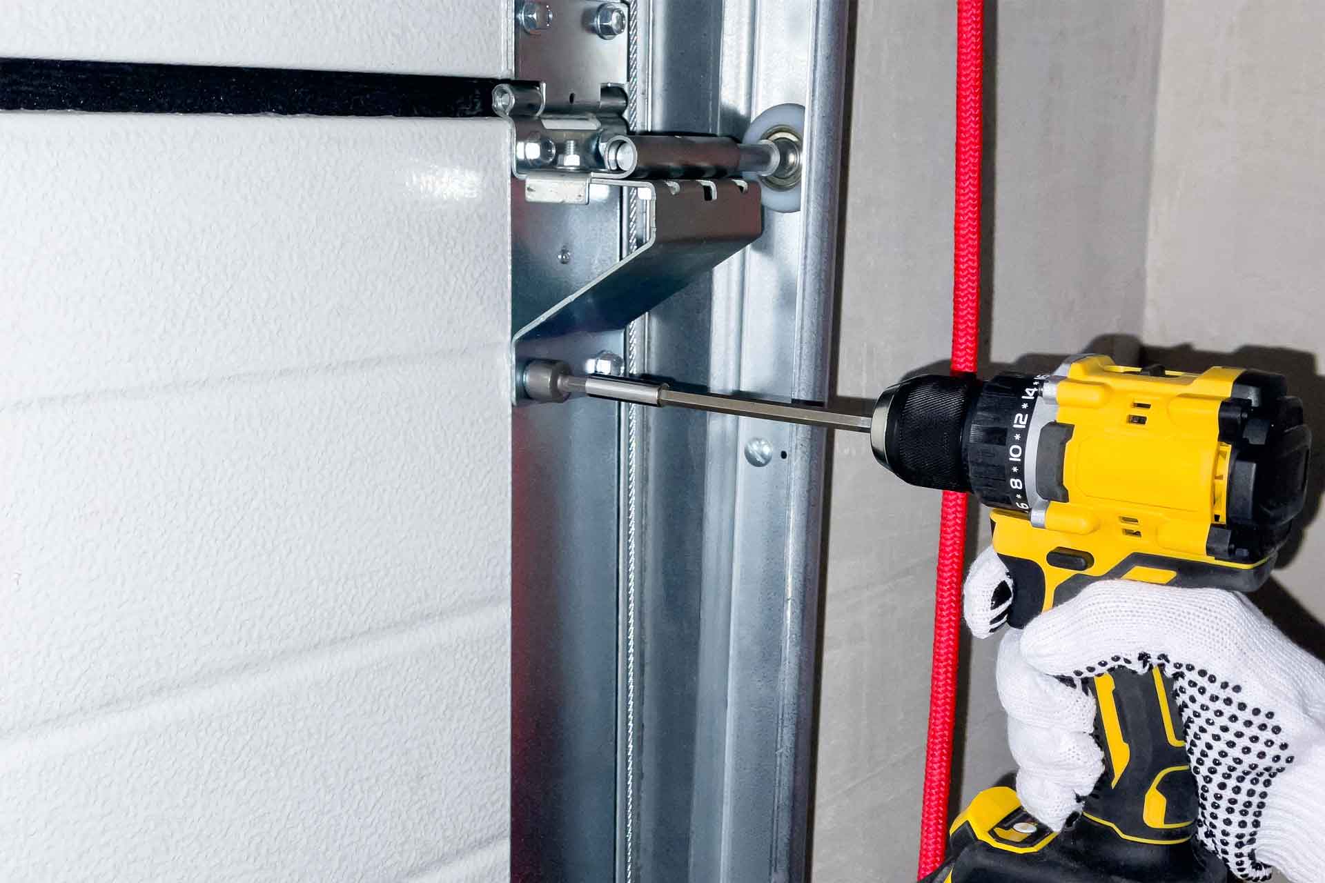 Garage door repair technician using a power drill to install a new garage door