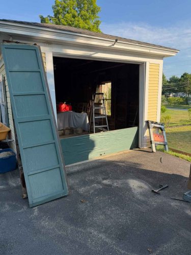 An old, chipped, sun-faded overhead door on a storage shed